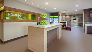 A hotel reception area with a reception desk, a display of green apples, and a 'Home 2 Suites by Hilton' sign. - Home2 Suites by Hilton Alameda Oakland Airport (Alameda)