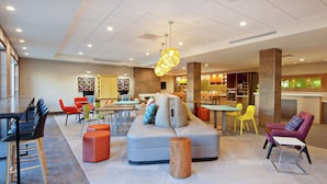 A modern lounge area with a sofa, chairs, and a dining table. - Home2 Suites by Hilton Alameda Oakland Airport (Alameda)