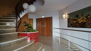 Un escalier orné d’un jardinier rouge et d’un tableau accroché au mur.