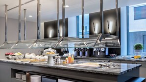 Una cocina moderna con encimera de mármol, electrodomésticos de acero inoxidable y una zona de buffet con puertas de vidrio.
