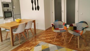 Une cuisine compacte dotée d’appareils électroménagers modernes, une table à manger avec des chaises et un tapis aux couleurs vives.