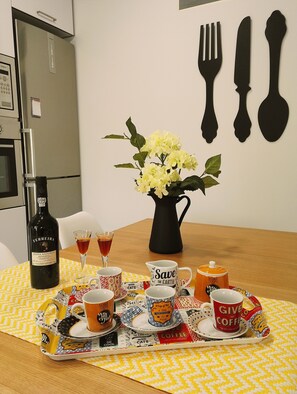 A dining table with a bottle of wine, glasses, and a tray with coffee cups and a mug.