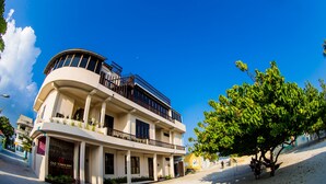 A multi-story hotel with balconies, a sign reading "Old Town Inn," and a tree-lined street.