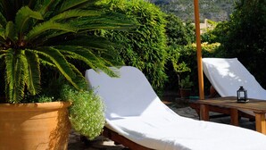 A sun lounger with a white cover, a large umbrella, and a potted plant. - Idyllic casita in Soller with garden and pool (Sóller)