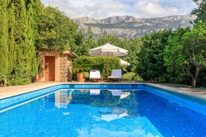 A swimming pool with tiled blue water, surrounded by lush greenery and a mountain backdrop. - Idyllic casita in Soller with garden and pool (Sóller)