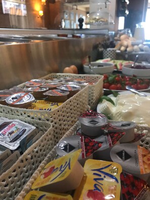 Un bufé con diferentes alimentos, incluyendo yogur, queso y frutas.