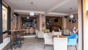 Ruime loungeruimte met verschillende zitmogelijkheden, waaronder barstoelen en fauteuils, en een bar op de achtergrond.