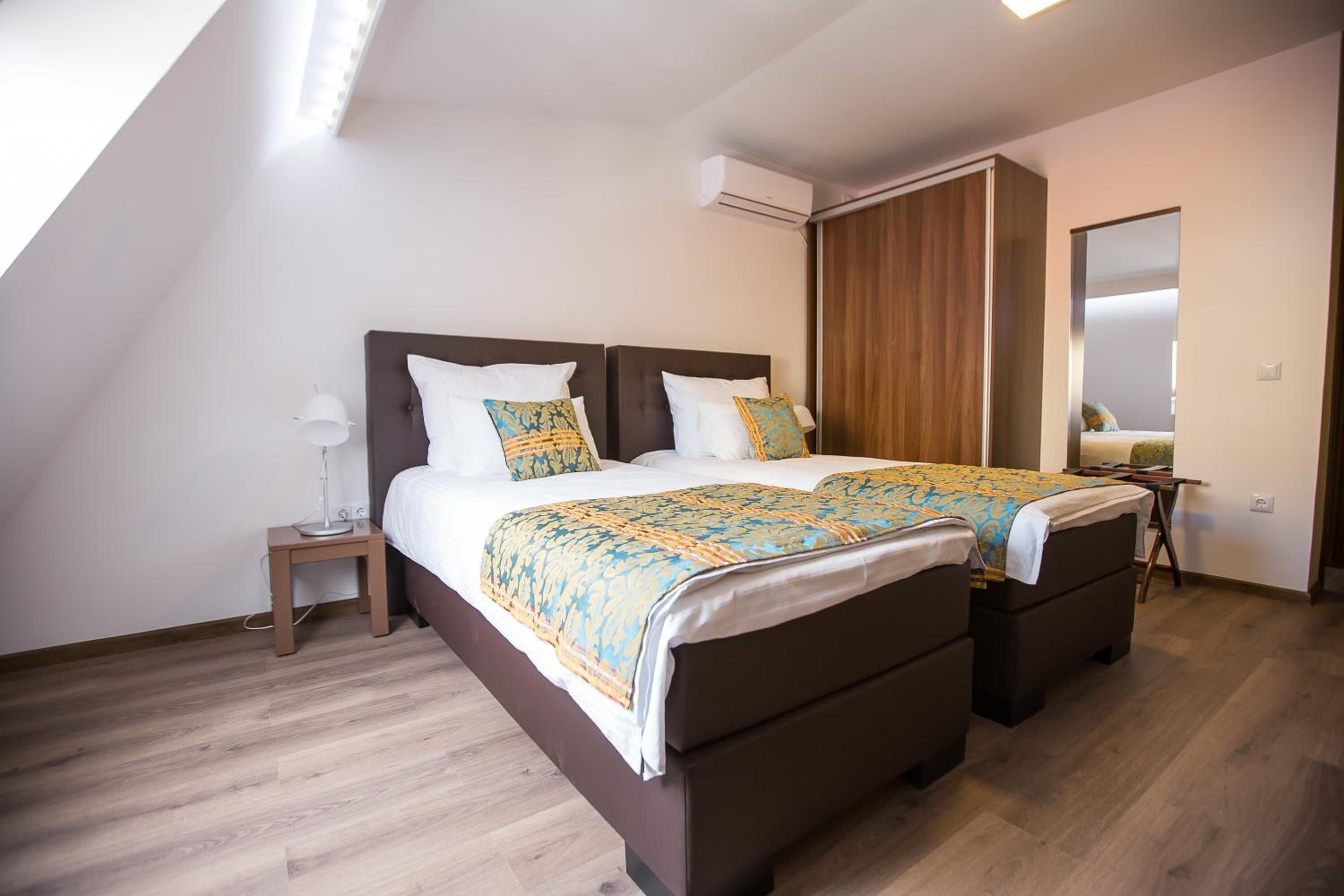 A bedroom with a large bed, a wardrobe, a bedside table with a lamp, and a mirror.