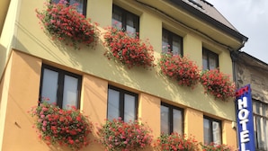 Een hotel met meerdere bloembakken aan de gevel, een bord met 'Heartland Hotel Cafe & Restaurant' en een bordje 'City Hotel'.