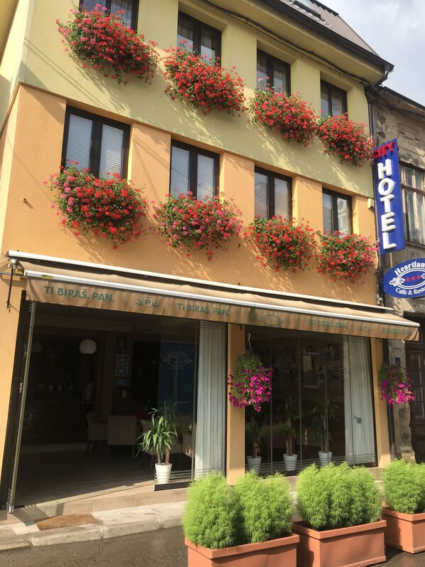 Un hotel con varios maceteros florales en la fachada, un letrero que dice 'Heartland Hotel Cafe & Restaurant' y un letrero que indica 'City Hotel'.
