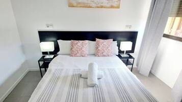 Camera d'albergo con un letto, due lampade ai lati, una testiera e una finestra con tende.