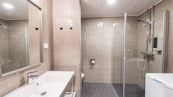 Un baño moderno con ducha envuelta en vidrio, un lavamanos blanco y un inodoro.