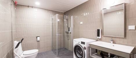 A modern bathroom with a toilet, shower, and washing machine.