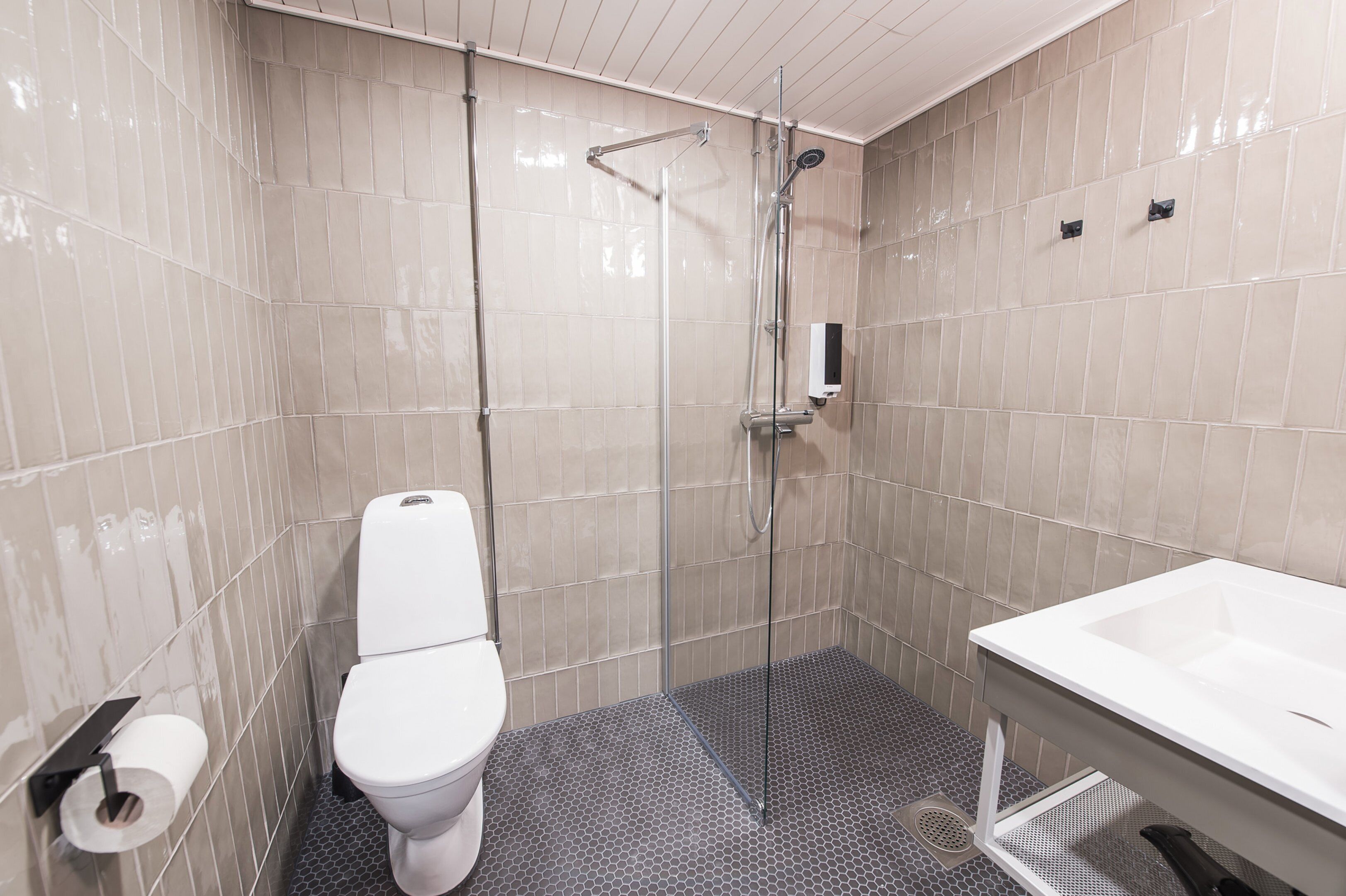 A bathroom with a toilet, shower, and sink.