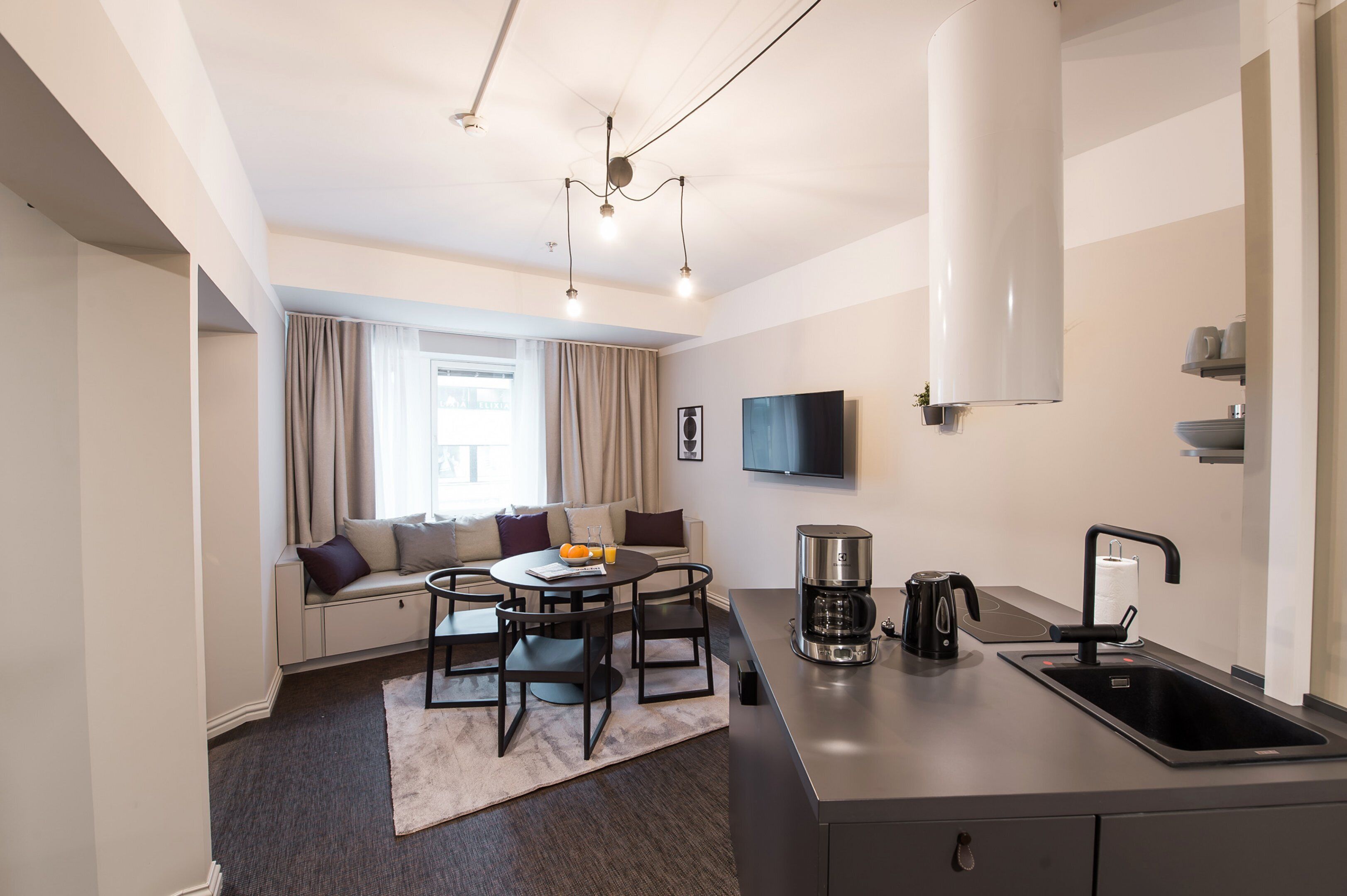A modern kitchen with a sink, coffee maker, and a dining area with a table and chairs.