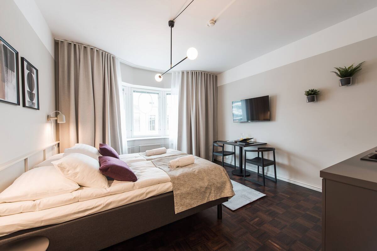 A modern bedroom with a bed, bedside table, and a TV mounted on the wall.