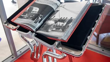 Un livre contenant des photographies en noir et blanc de voitures anciennes, présentées sur un présentoir en chrome.