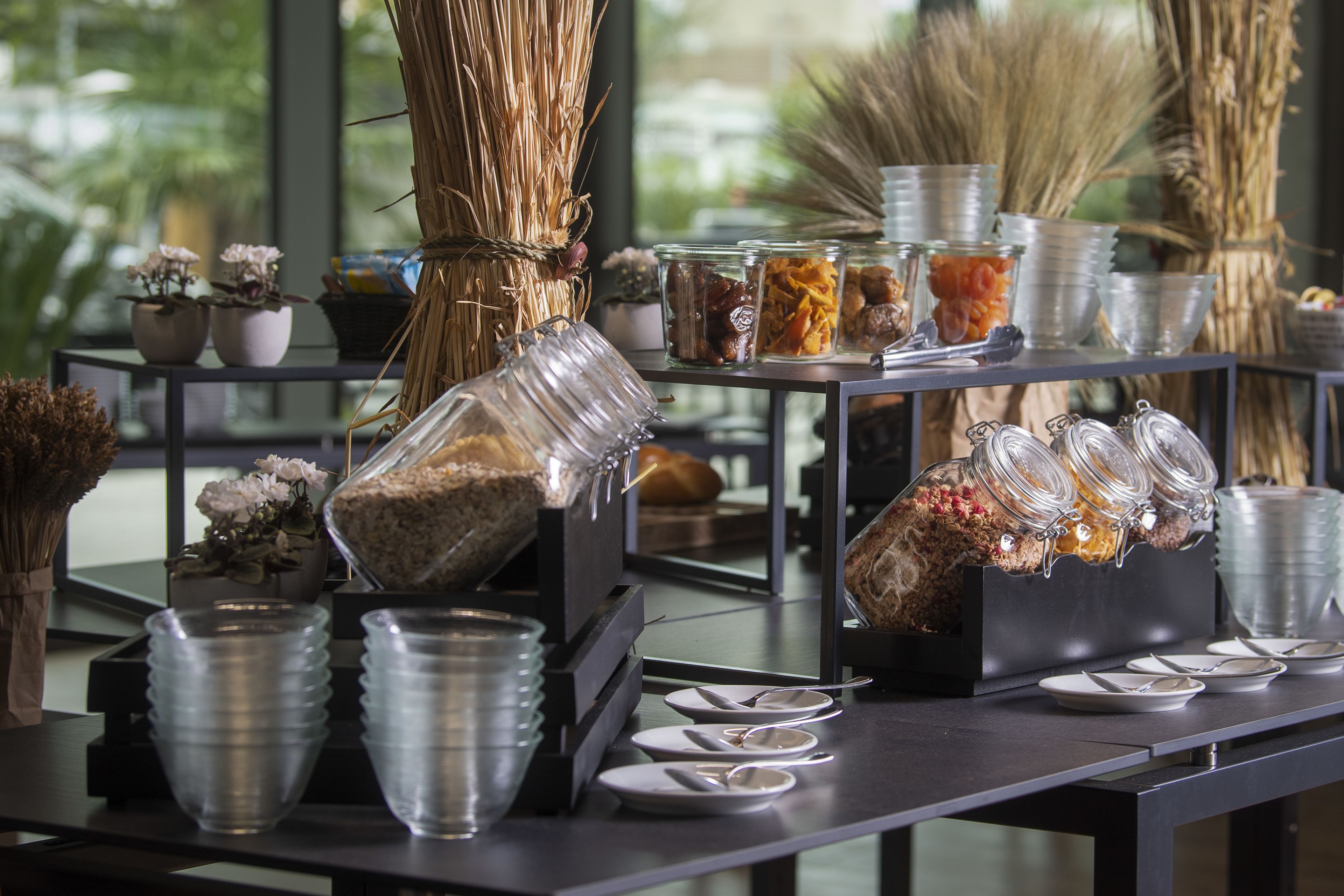 Un buffet proposant une variété de plats présentés dans des récipients en verre, accompagnés d’assiettes et de couverts.