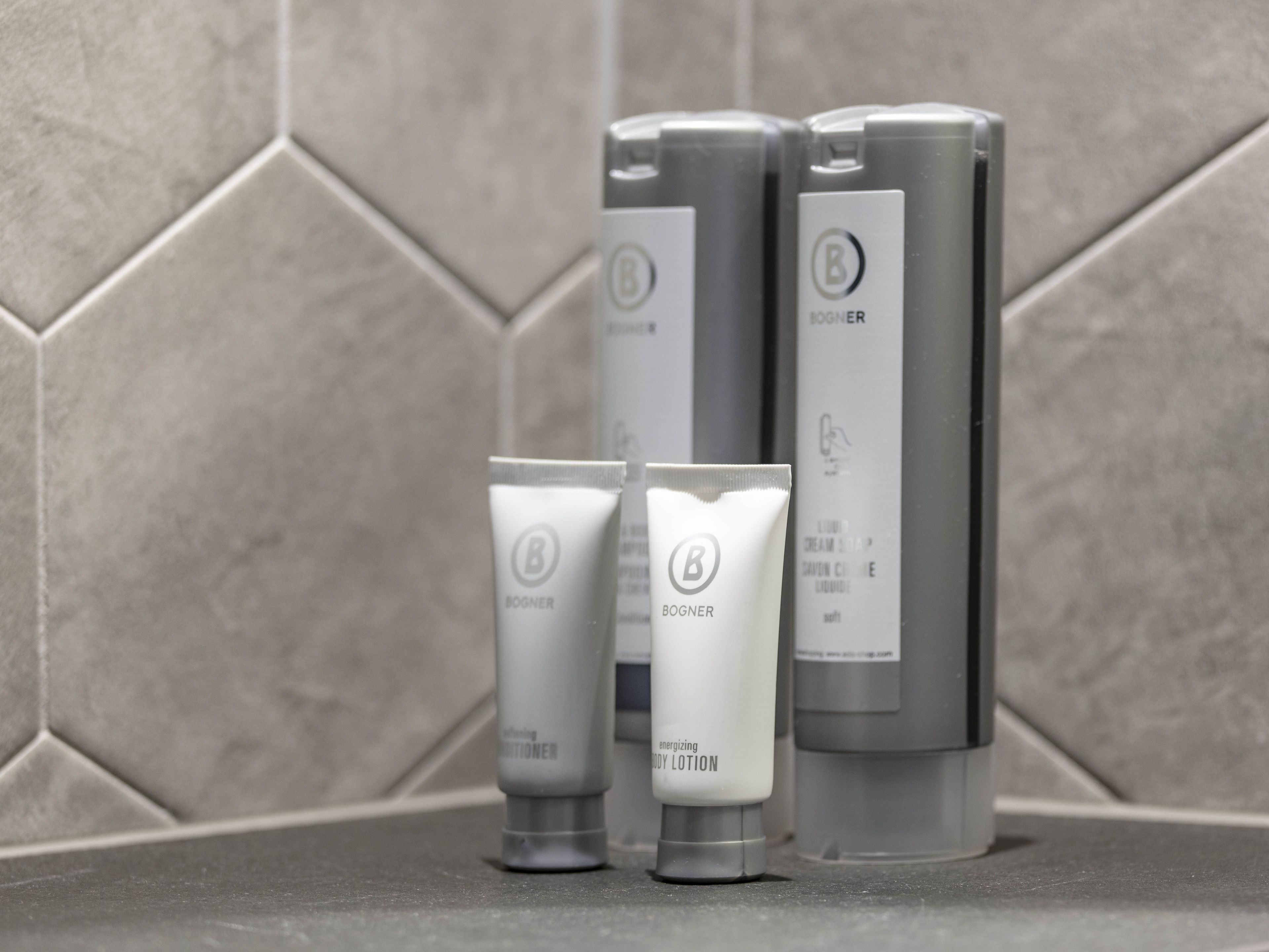 Four skincare products with the brand name 'BOGNER' on a tiled surface.