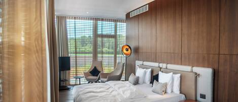 A modern bedroom with a large bed, a side table, a chair, and a lamp.