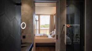 A modern hotel room with a bed, a small bedside table, and a window with curtains. - Hotel Meilenstein (Langenthal)