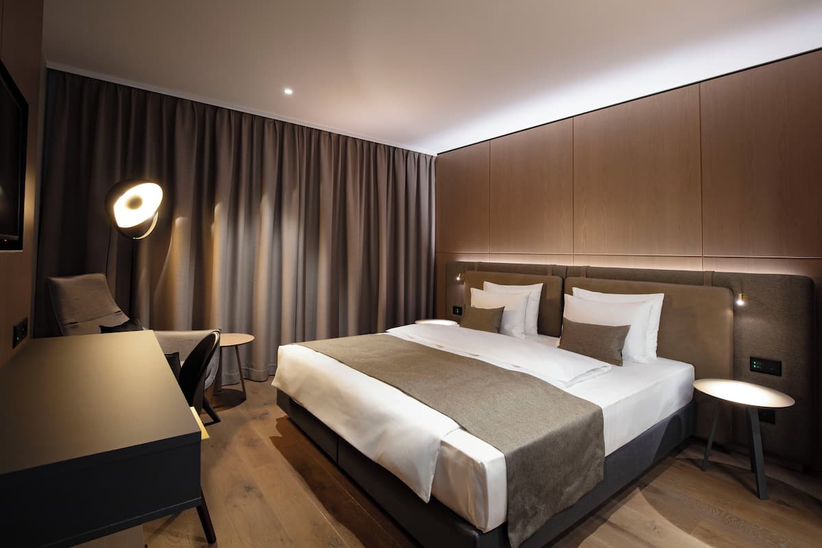 Una habitación de hotel moderna con una cama grande, un escritorio y una silla.