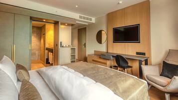 Una habitación de hotel moderna con una cama grande, un escritorio, una silla, un televisor y un armario.