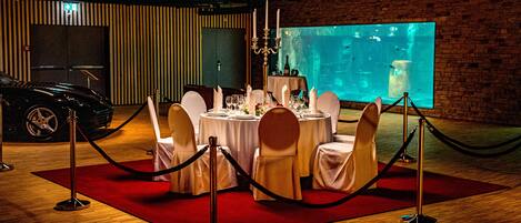 Un montaje formal para el comedor, con mesas redondas, manteles blancos y sillas doradas.