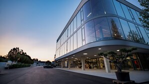 A modern building with a curved glass facade, a spacious entrance area, and a parking lot. - Hotel Meilenstein (Langenthal)