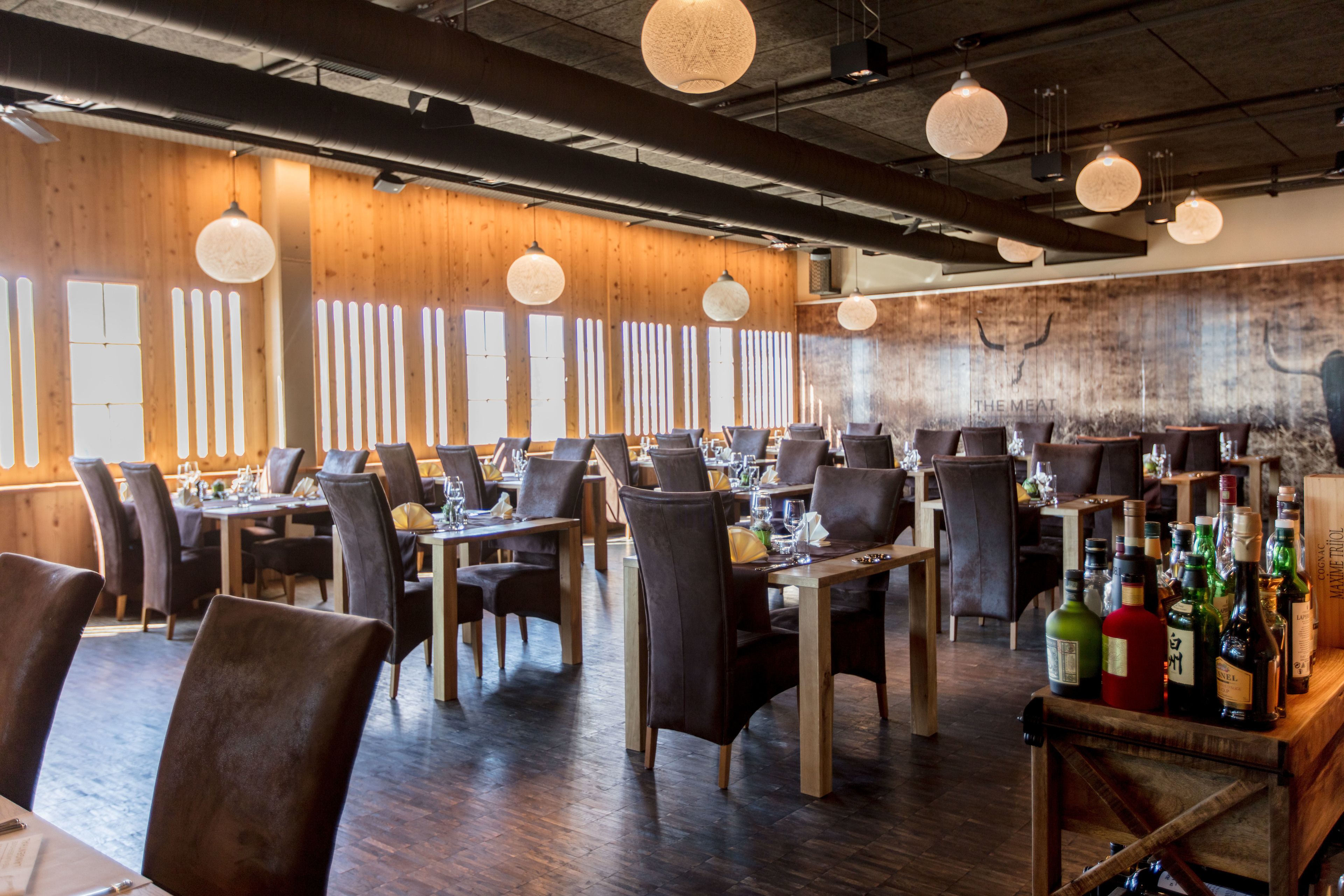 A restaurant with wooden walls, multiple tables, and hanging spherical light fixtures.
