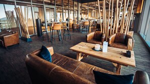 A modern interior with leather sofas, wooden tables, and a bar area with stools. - Hotel Meilenstein (Langenthal)