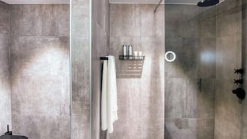 A modern bathroom with a glass shower enclosure, a black sink, and a towel rack.