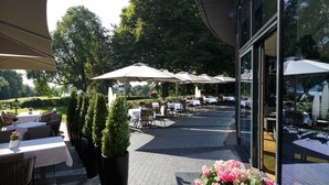 Un espace extérieur aménagé en terrasse, avec des tables et des chaises, des parasols et des plantes en pot.