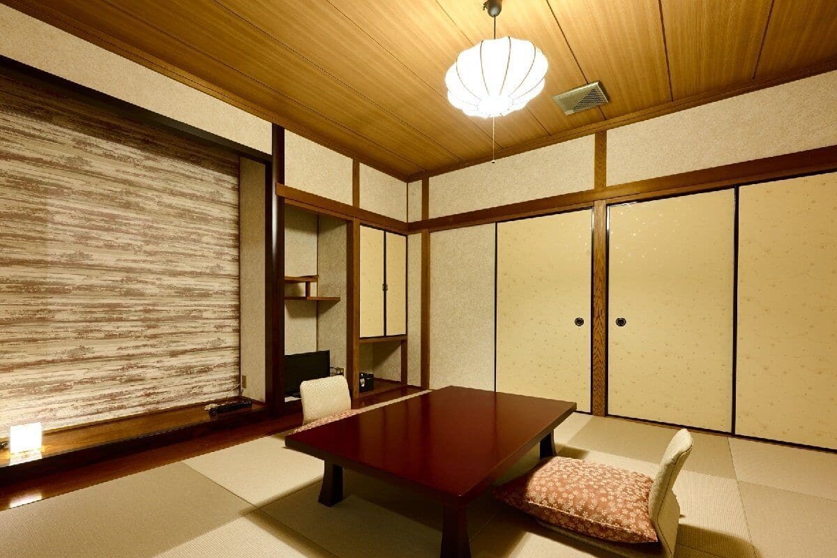Ein traditioneller japanischer Raum mit Tatami-Böden, einem niedrigen Holztisch und Schiebetüren.