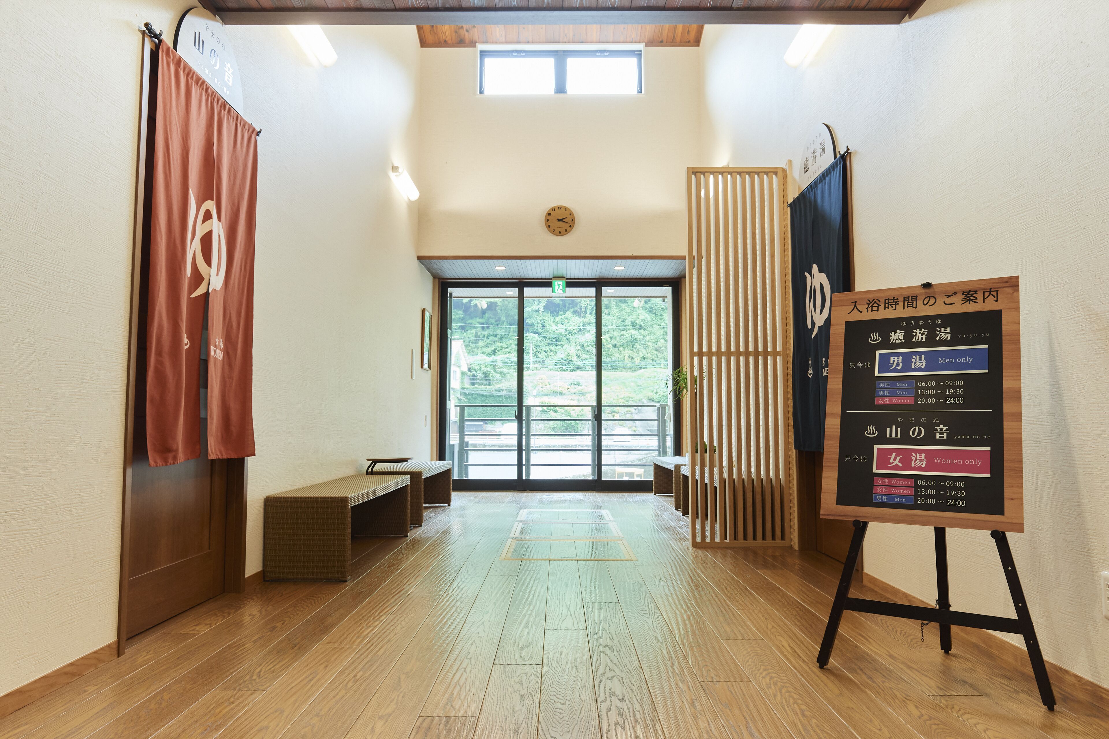 A reception area with a wooden floor, a reception desk, and a signboard with operating hours.