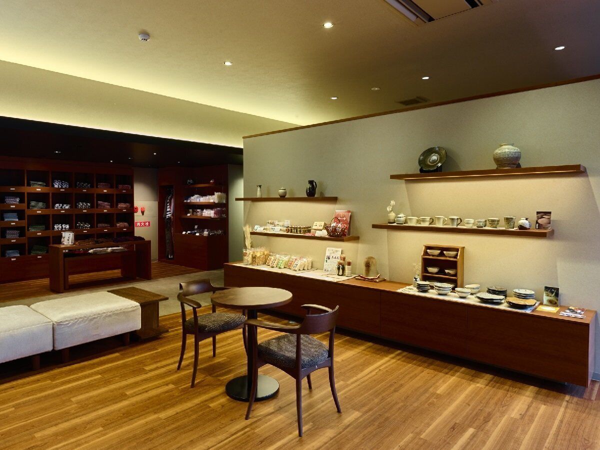 Un café acogedor con muebles de madera, un espacio de asientos y estantes que exhiben cerámica.