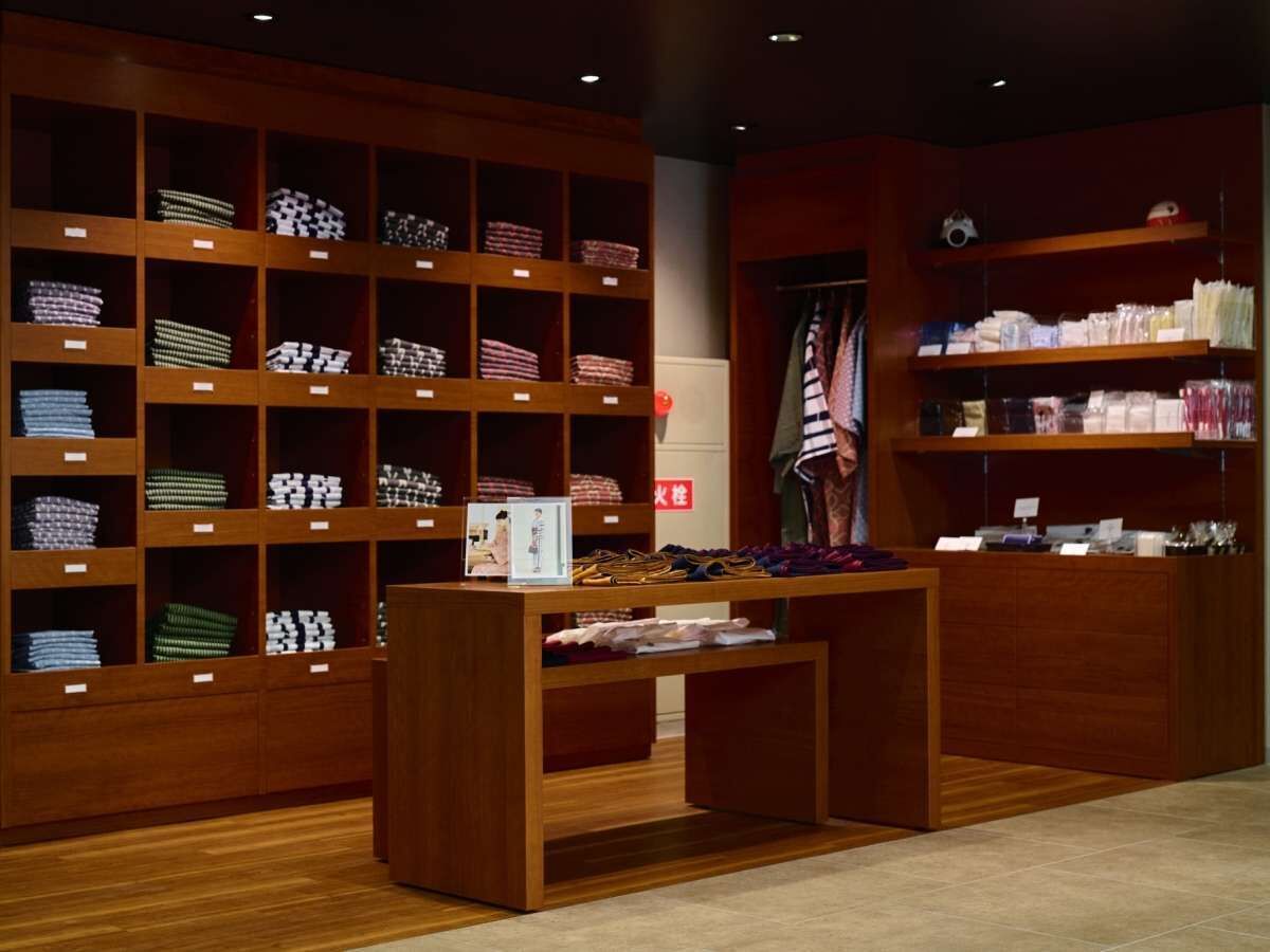 A retail store with wooden shelving displaying folded clothes and accessories.