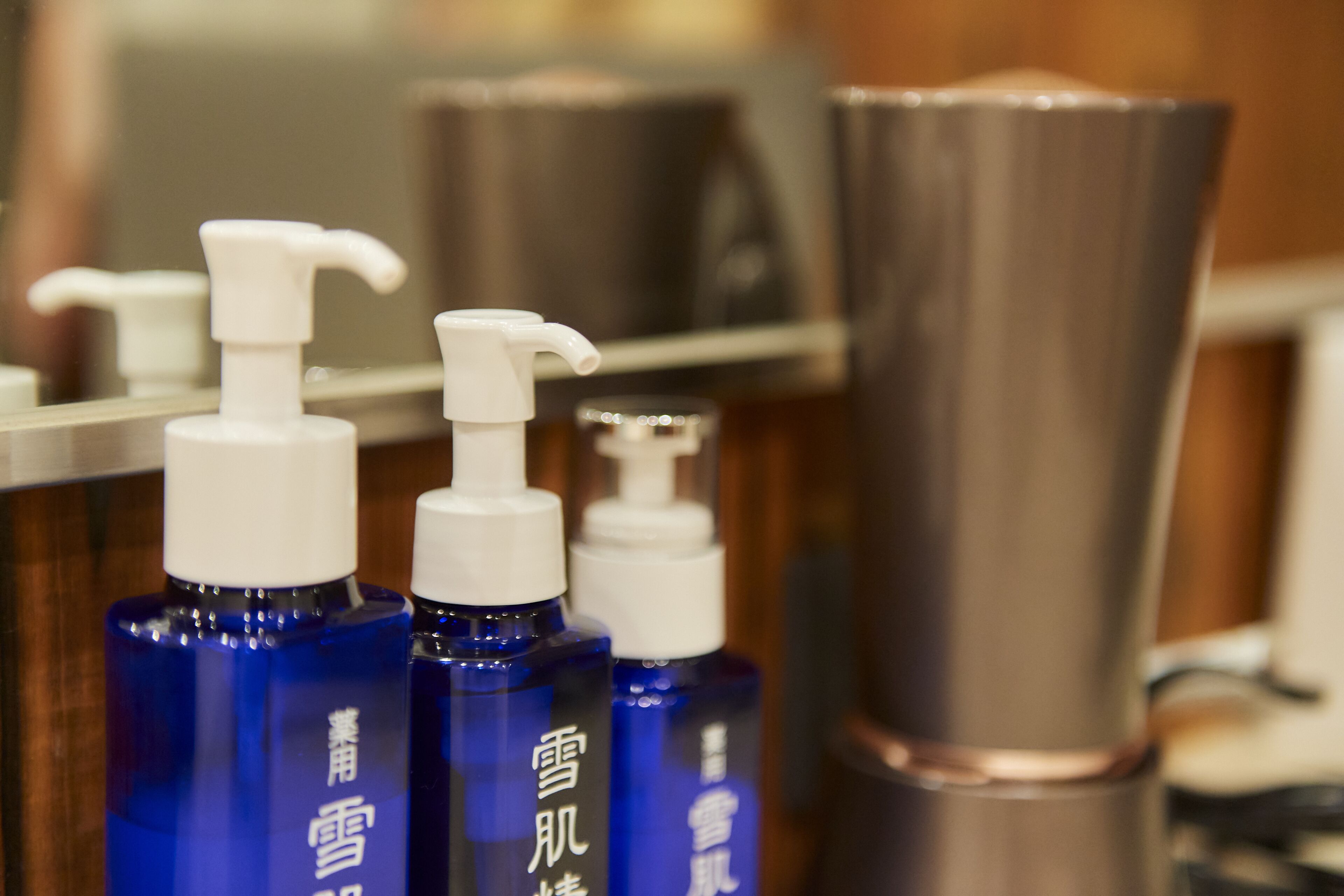 Three blue bottles with white pumps, likely containing skincare products, in a bathroom setting.
