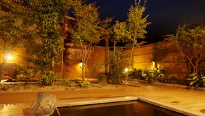 A nighttime view of a courtyard with a pool, surrounded by trees and a building with warm lighting. - Amagase Onsen Seitenkaku (Hita)