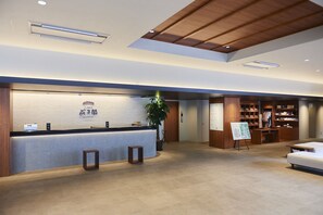A reception area with a counter, a plant, a wooden desk, and a seating area. - Amagase Onsen Seitenkaku (Hita)