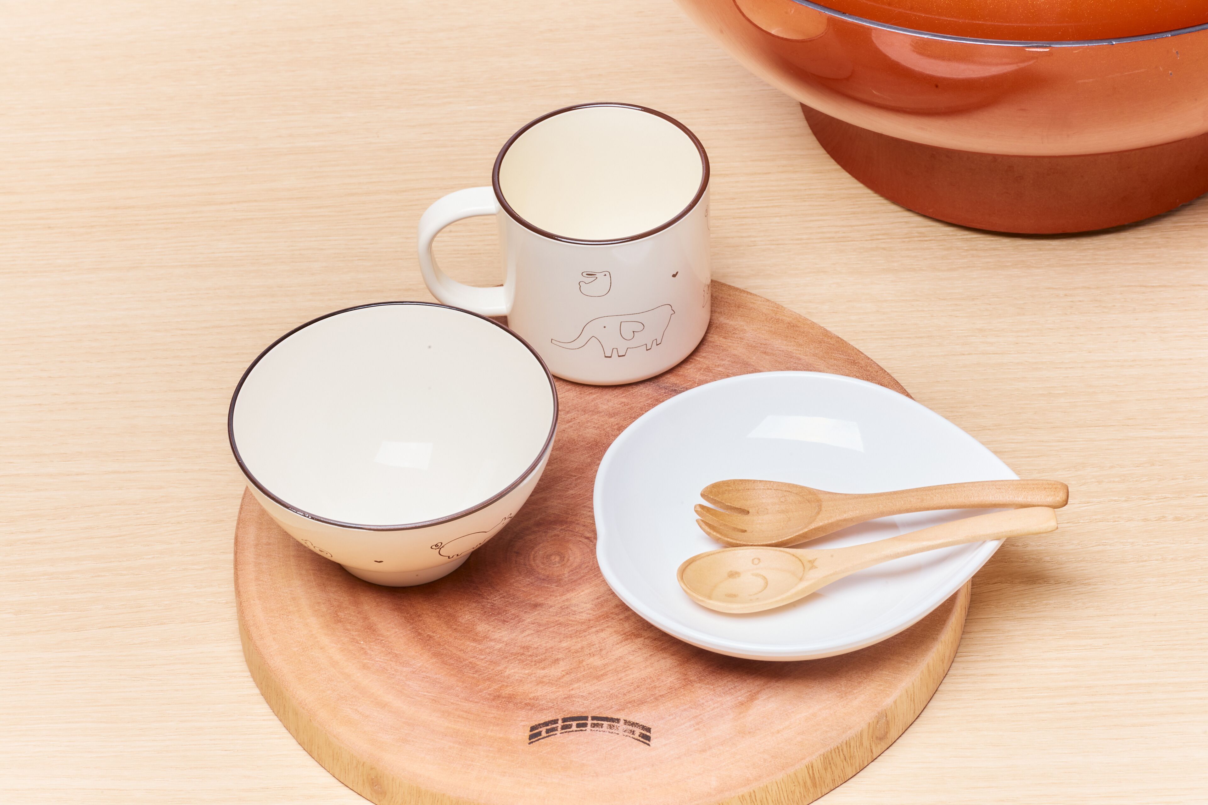 A wooden tray with a white mug, a ceramic plate, and two wooden spoons.