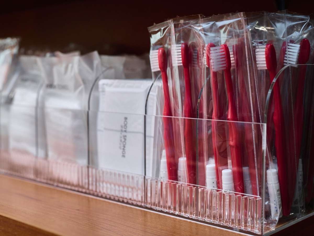 A row of toothbrushes in clear plastic bags on a shelf.