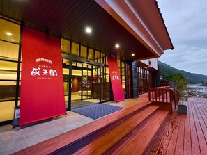 A hotel with a wooden deck, large windows, and red signage. - Amagase Onsen Seitenkaku (Hita)