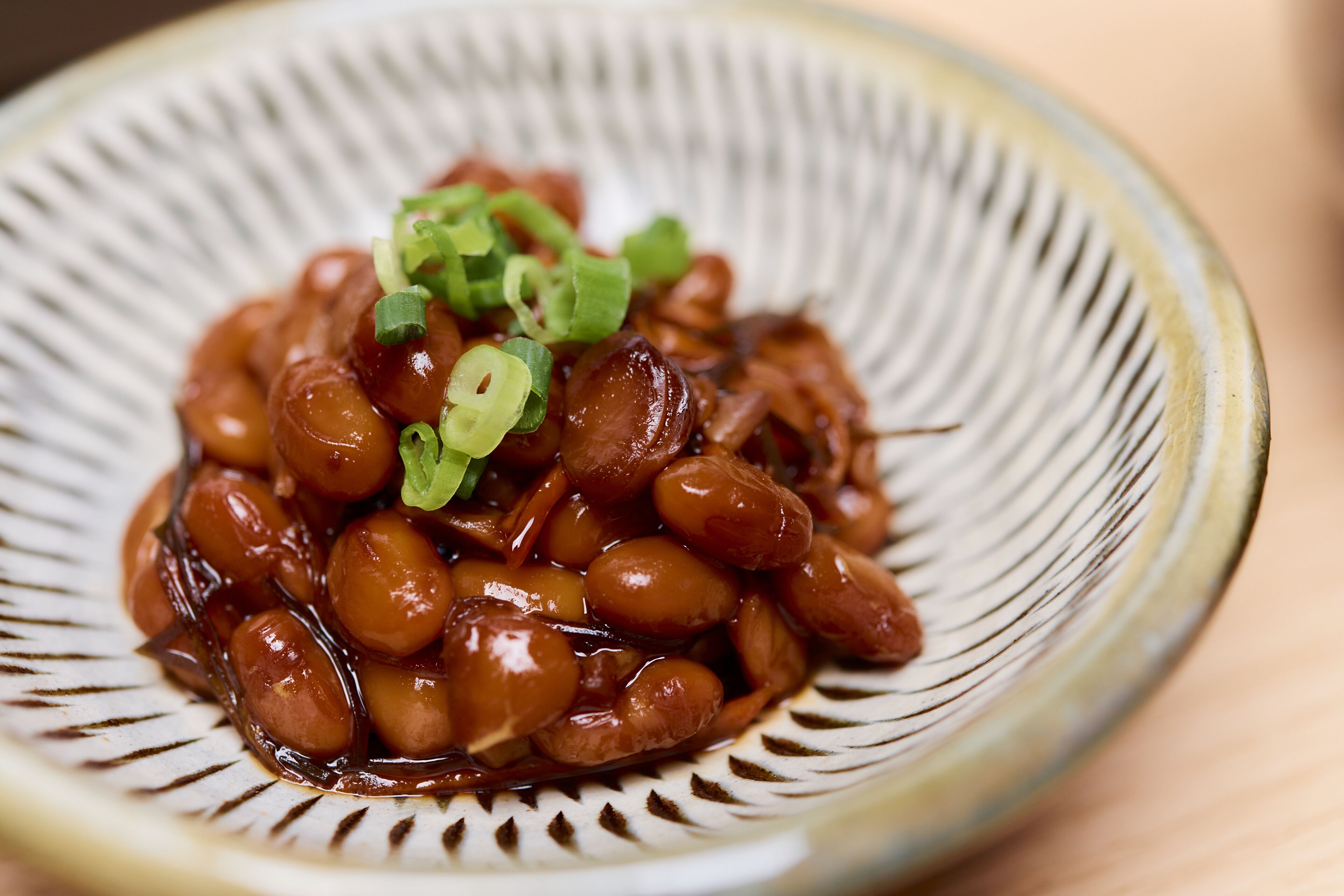 A bowl of glazed beans garnished with green onions.