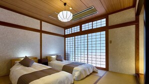 A traditional Japanese-style room with tatami flooring, two beds with white bedding, a shoji screen window, and a ceiling fan. - Amagase Onsen Seitenkaku (Hita)