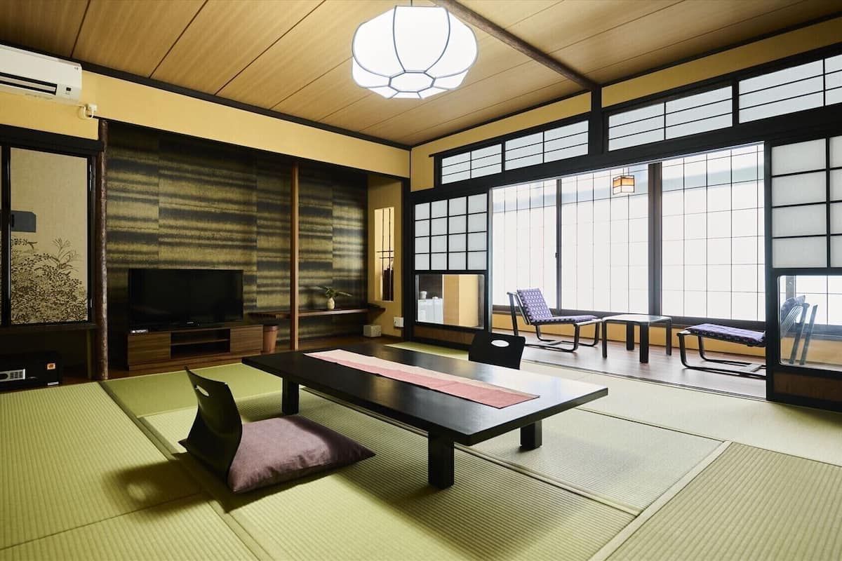 Um quarto japonês tradicional com tatames, televisão e portas deslizantes.
