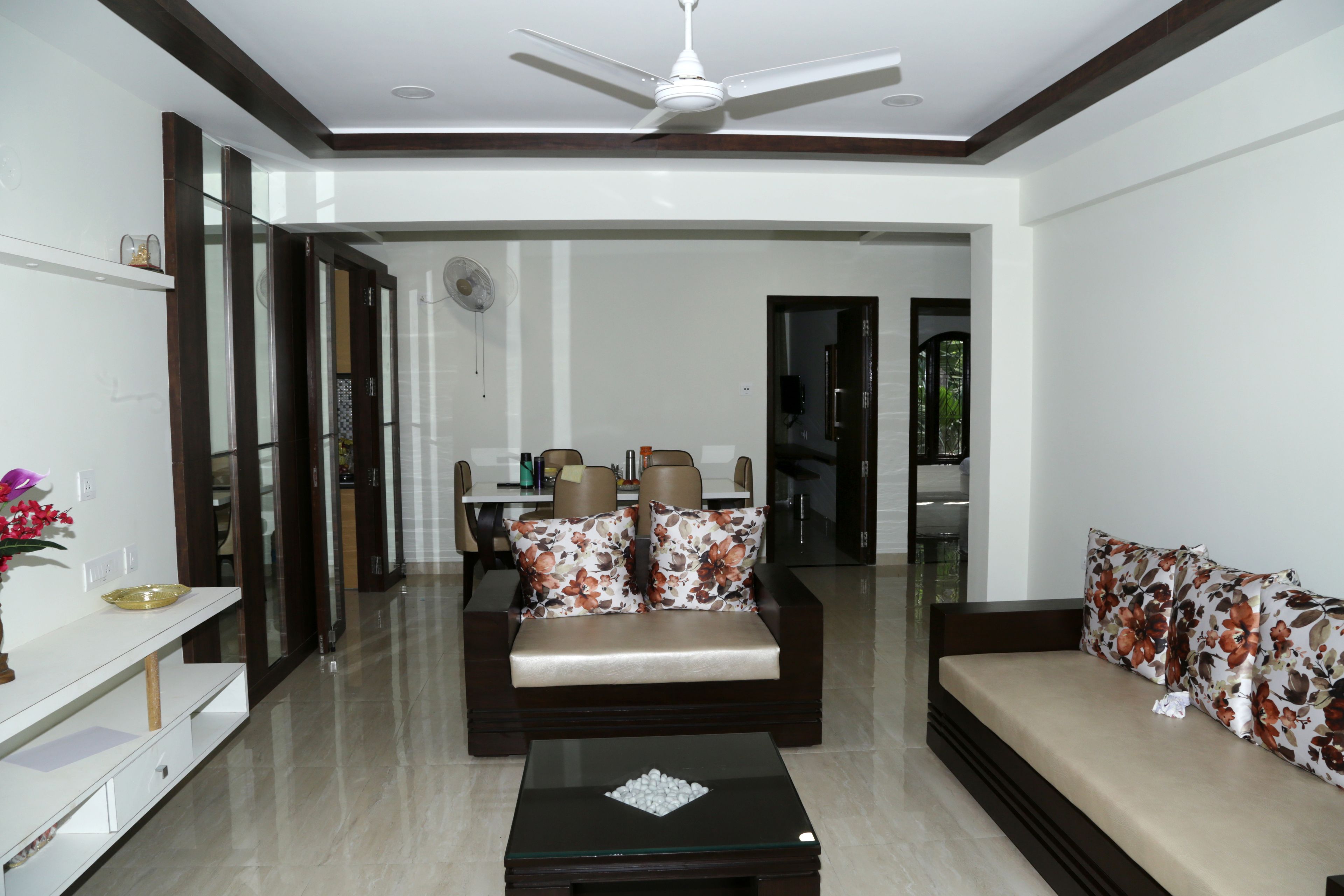 A modern living room with a sofa, a coffee table, and a dining area in the background.