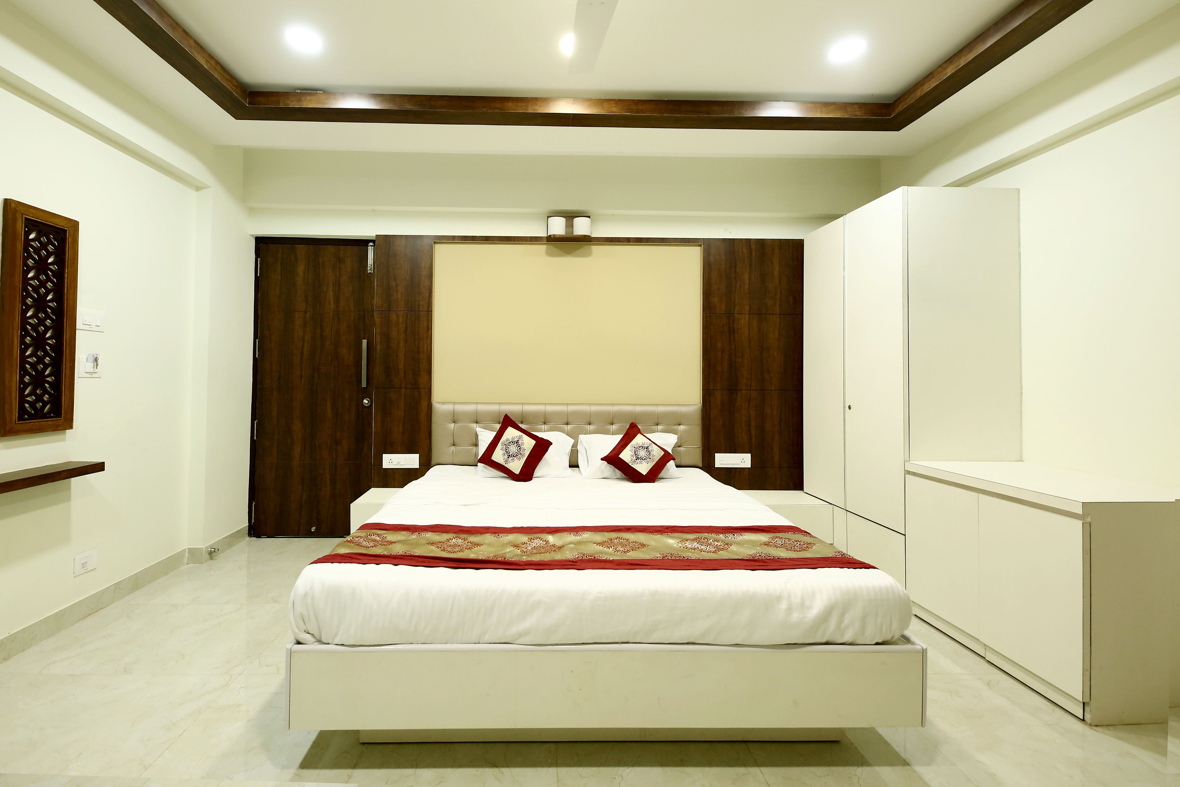 A modern bedroom with a large bed, wooden wardrobe, and a white wardrobe.