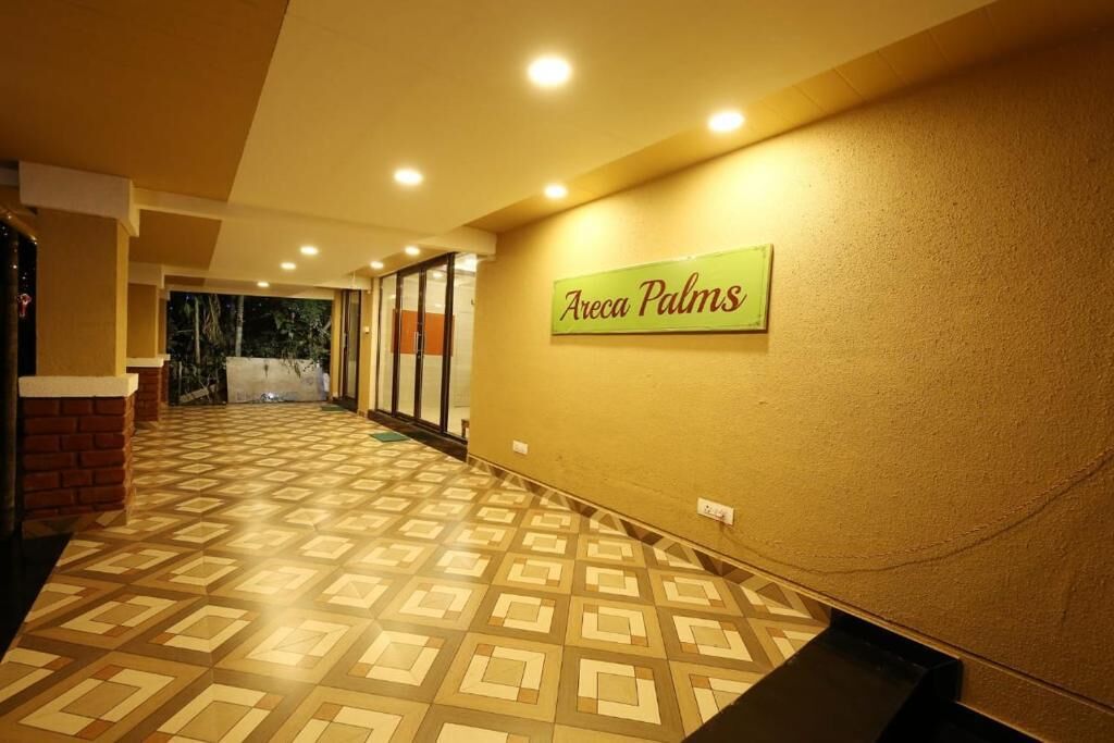 Un corridoio con pavimento decorato, un cartello con la scritta 'Areca Palms' e un muro di mattoni a sinistra.