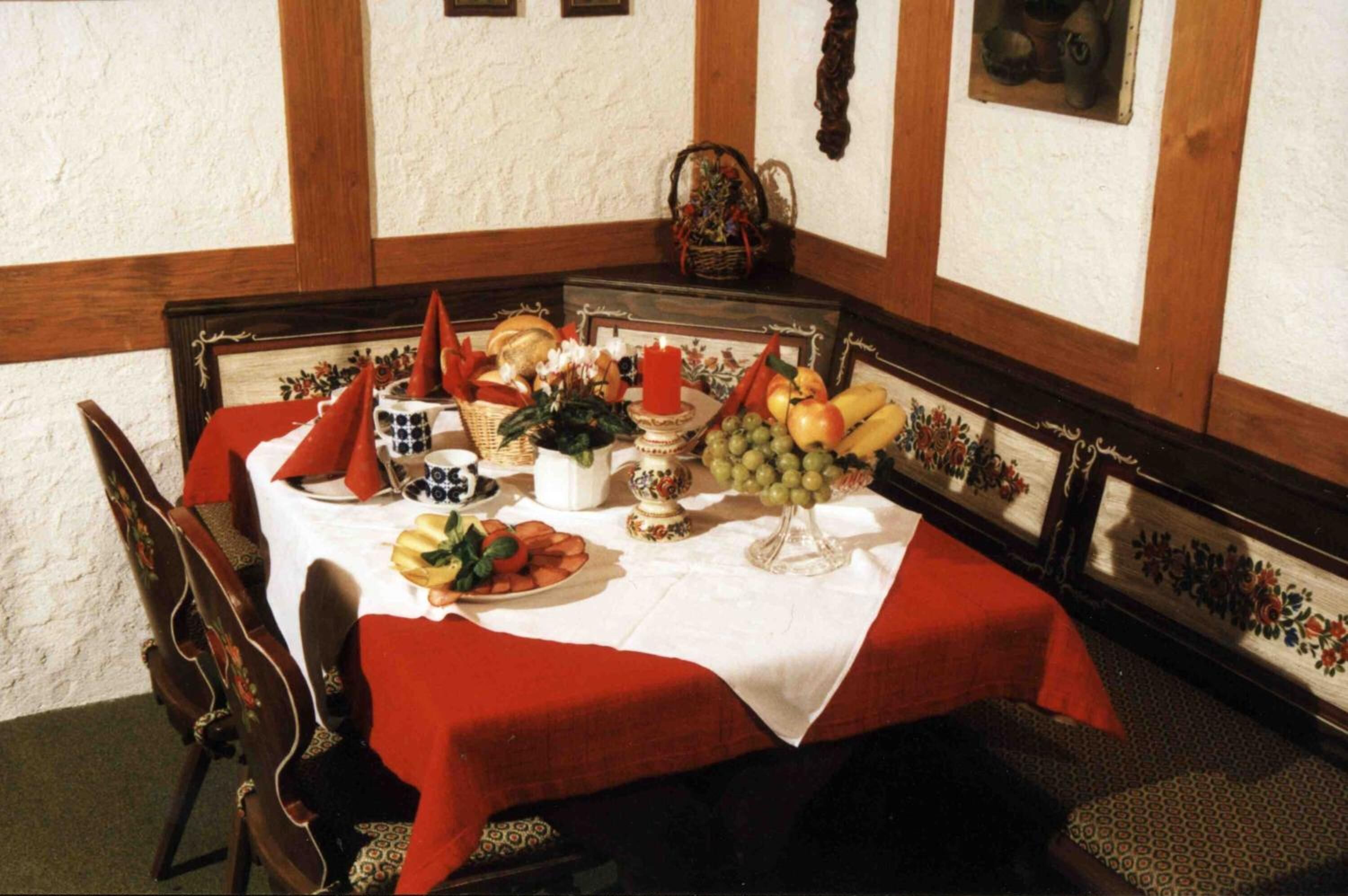 A dining table set with a white tablecloth, red napkins, and various fruits and vegetables.